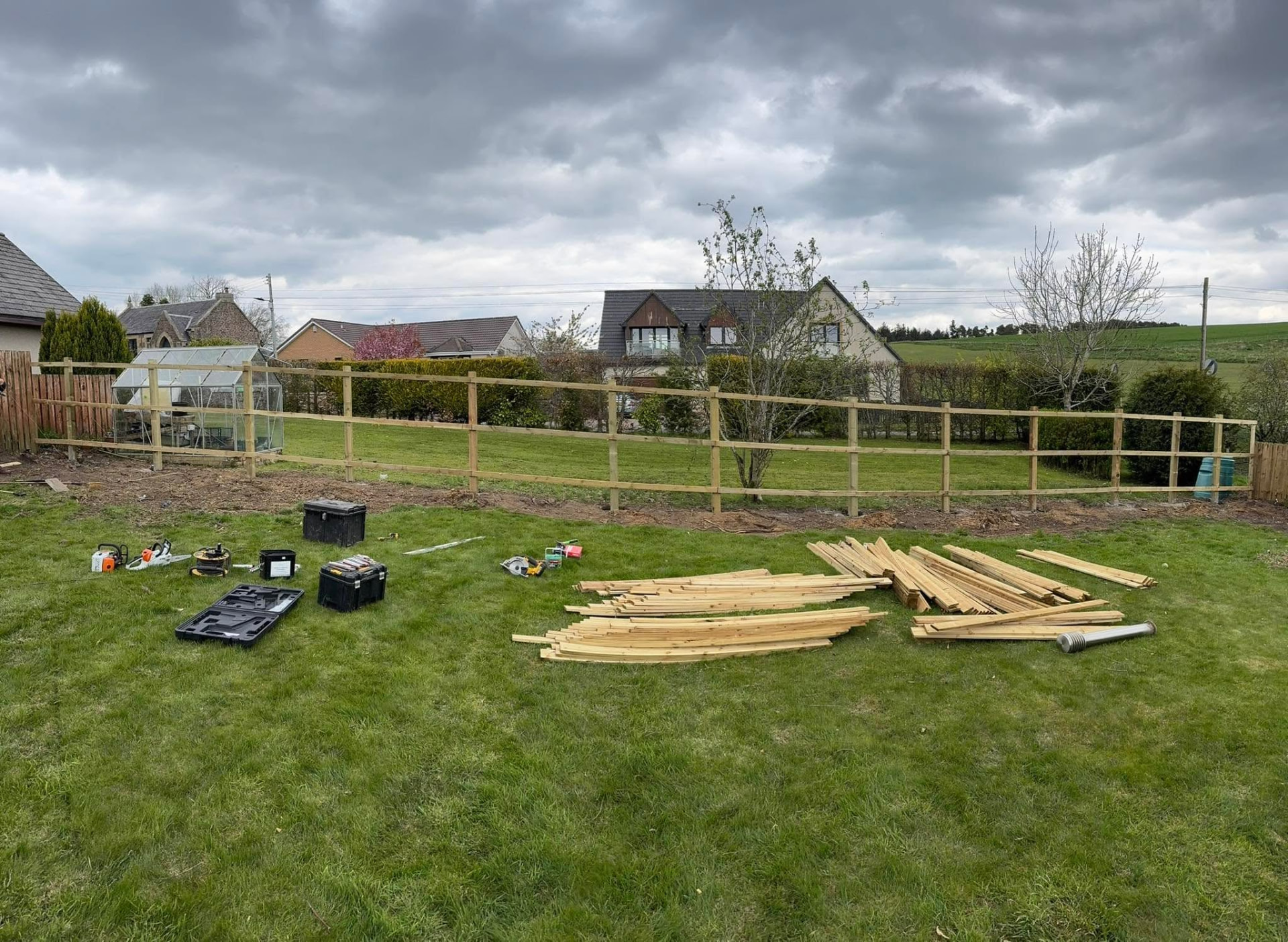Fence posts and rails installed with timber boards laid out ready to fit