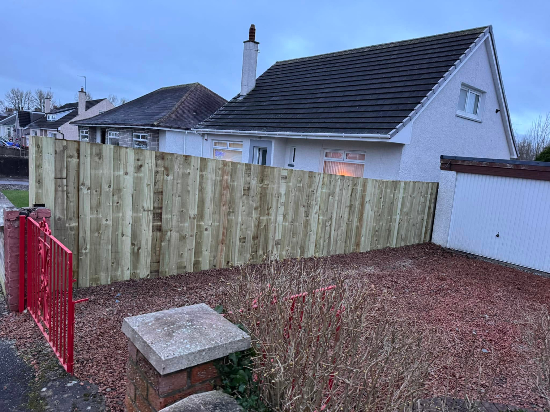 Completed close-board timber fence beside a house driveway and garage
